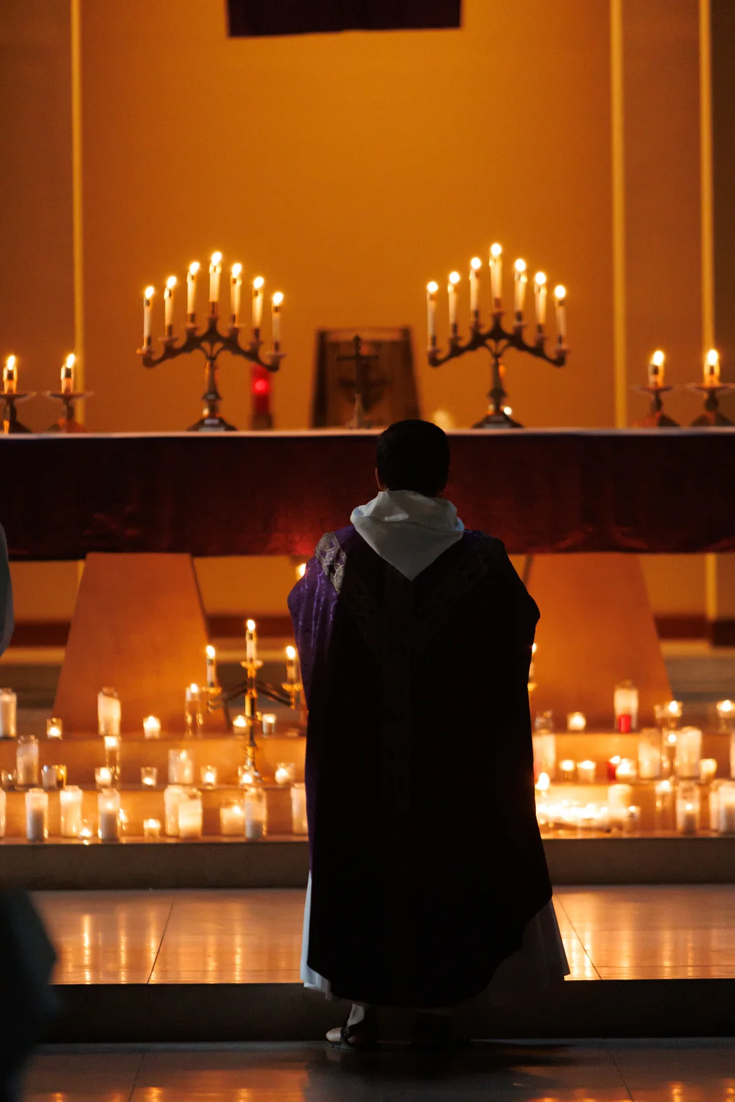 Priest standing before a candlelit altar